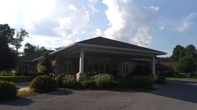 Entrance of a senior living facility surrounded by greenery