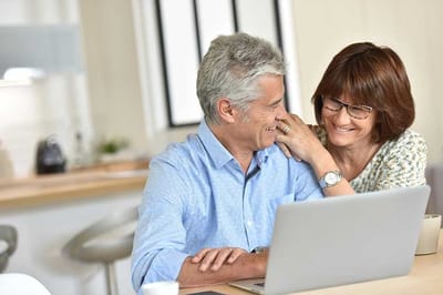 Couple enjoying time together at a computer in a cozy environment.