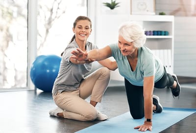 A staff member assisting a senior resident in a fitness session