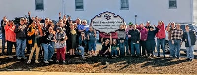 Residents and staff celebrating in front of the facility
