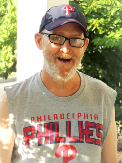 A smiling man wearing a Phillies shirt and cap