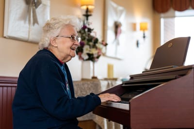 Resident enjoying music at a piano in a common area