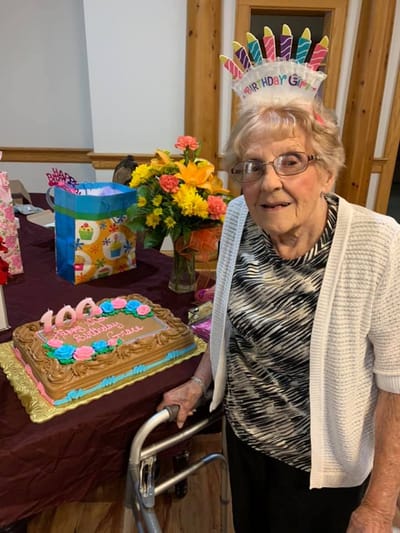 Resident celebrating 100th birthday with cake and flowers
