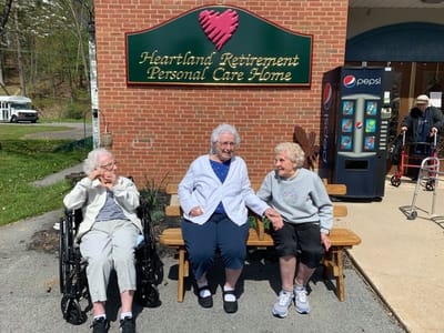 Three elderly women sitting outside the facility
