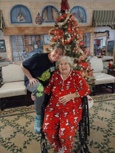 Resident and staff member celebrating by the Christmas tree