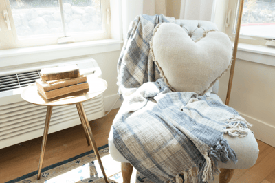 A cozy chair with a heart-shaped pillow and books