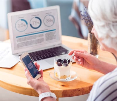 Senior woman enjoying dessert while using a smartphone