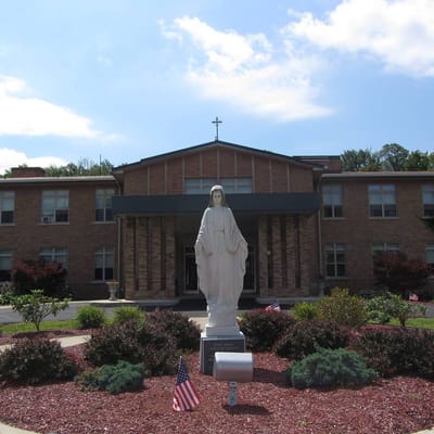 Exterior view of St. Mary's Villa Residence with garden and statue