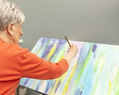 Brookdale South Bay, nursing home in Torrance, CA — Senior resident painting on a canvas in a studio
