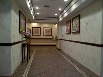 A well-lit hallway with framed artwork and floral arrangement