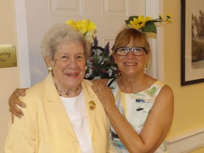 A resident and staff member smiling together indoors