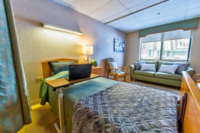 Brightly lit resident room with bed and seating area