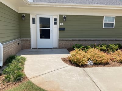 Entrance of a senior living facility showing the walkway and greenery