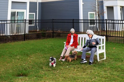 Two residents enjoying time with dogs in a garden