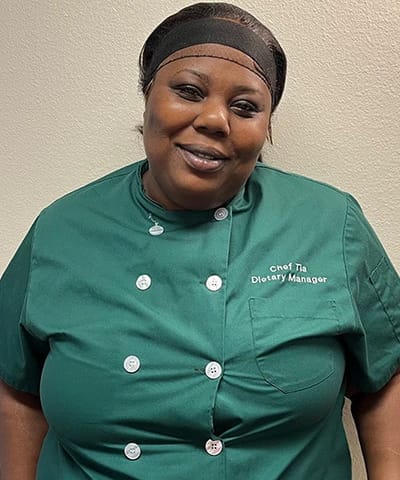 A dietary manager smiling in a green uniform