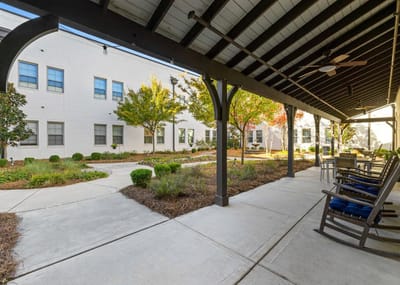 Covered patio area with rocking chairs overlooking landscaped garden
