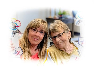 Two residents smiling with crafts in a common area