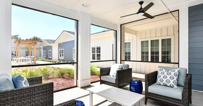 A screened porch with seating overlooking a garden