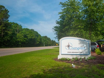 Facility sign by the roadside surrounded by greenery
