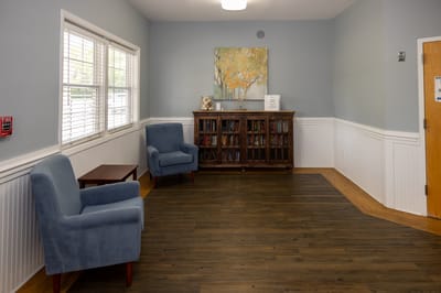 A cozy common area with blue chairs and a bookshelf