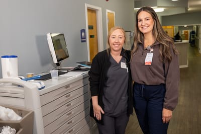 Two staff members smiling in a hallway