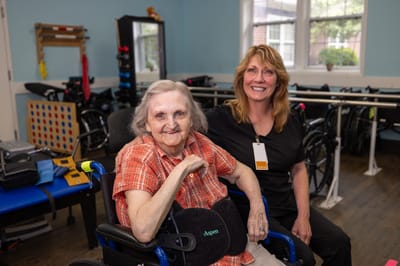A resident and staff member smiling in a therapy room
