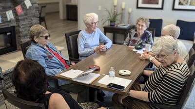 Residents engaged in conversation around a table in a common area