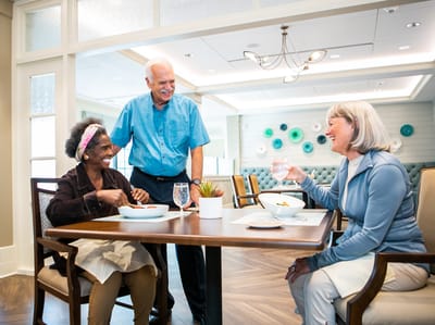 Residents enjoying a meal with staff in a dining area