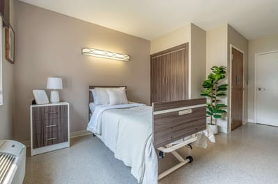 A well-furnished resident room with a hospital bed