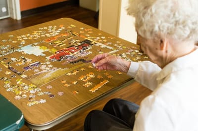 An elderly resident assembling a jigsaw puzzle indoors