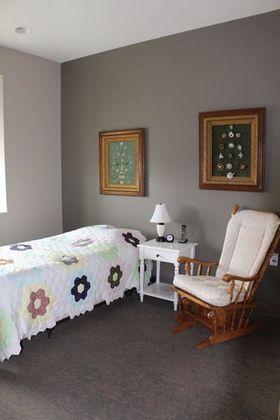 Cozy resident room with a quilted bed and rocking chair