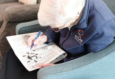 Resident enjoying a crossword puzzle in the lounge