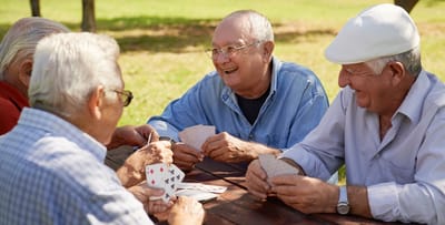 Seniors playing cards outdoors in a sunny setting