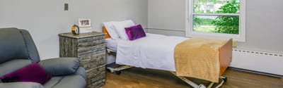A cozy resident room featuring a bed and chair