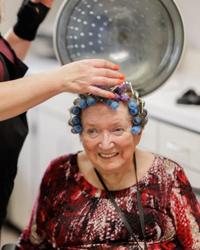Resident enjoying a hair styling session with curlers