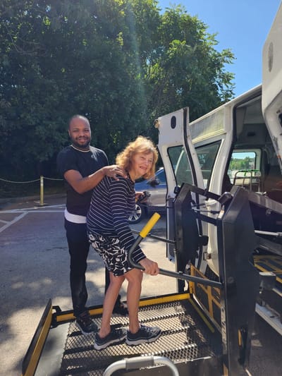 A caregiver assisting a resident into a van