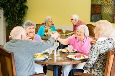 Residents enjoying a meal and toasting in the dining room