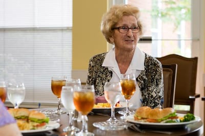 Senior resident enjoying a meal with others at a dining table