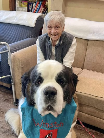 Resident smiling with a large dog in a common area