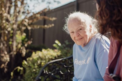 An elderly woman smiling in a garden