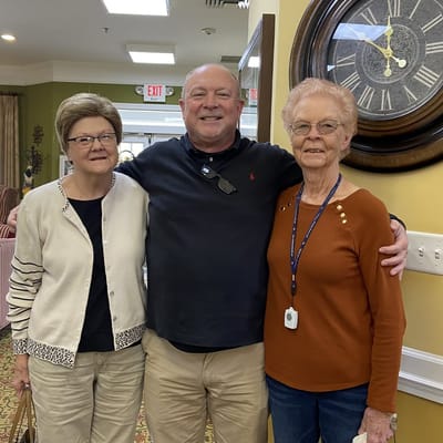 Two residents and a staff member smiling together