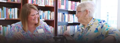 Staff member engaging with a resident in the library area