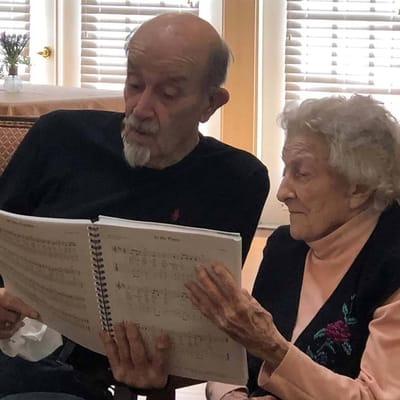 Two residents reading music together in a common area
