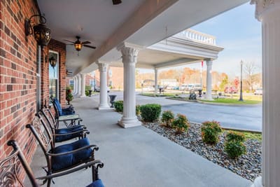 Covered entrance with rocking chairs and landscaping