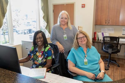 Three staff members smiling at the reception desk