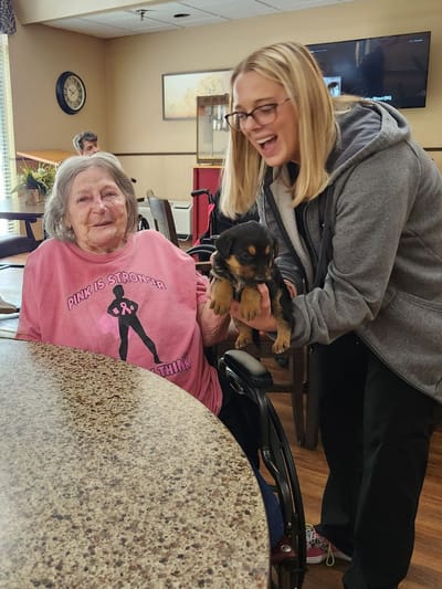 Resident and staff member enjoying time with a puppy