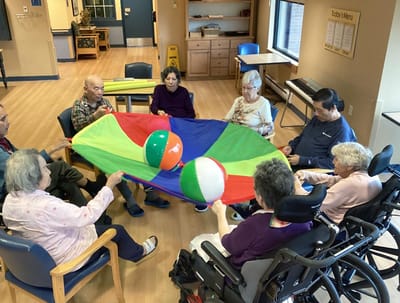 Residents playing with colorful parachute indoors