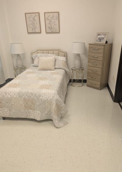 A well-decorated private resident room with a bed and lamps