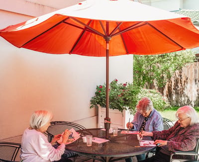 Residents enjoying arts and crafts under a patio umbrella