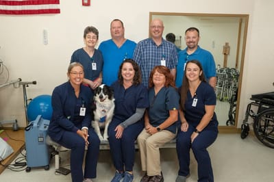 Staff posing with a therapy dog in a care facility